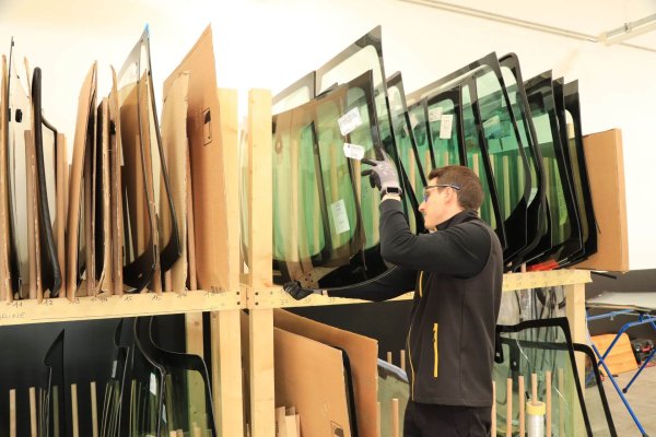 Technicien vitrage pose un pare-brise dans le stock