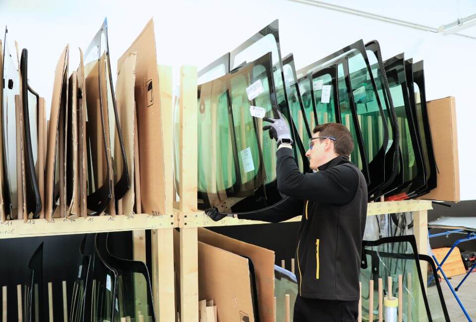 Technicien vitrage pose un pare-brise dans le stock